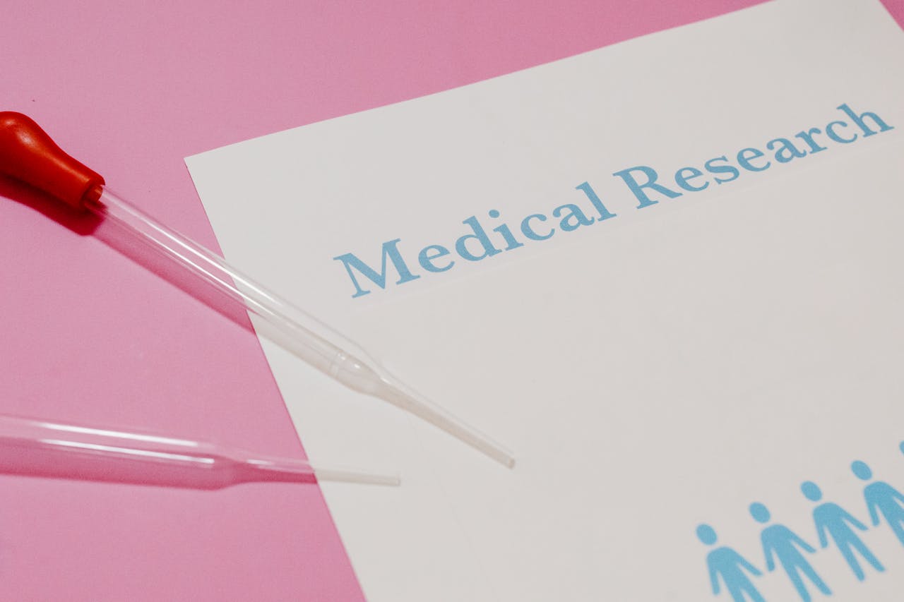 Close-up of a medical research document and pipette on a pink surface, highlighting scientific research and healthcare.