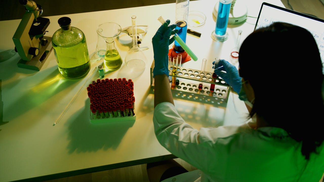 Researcher examines vials in a laboratory setting, engaging in scientific experiments.